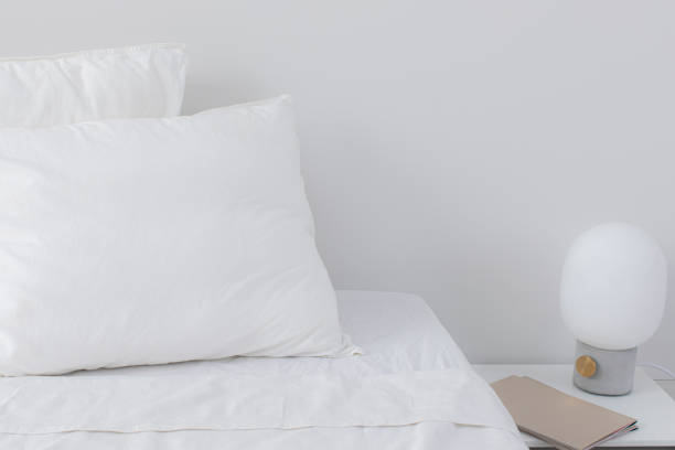 istock Fluffy White Pillows and a Lamp beside a Bed in a Hotel Room 1308295210