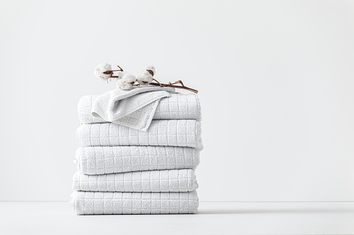 Neatly folded white cotton towels, a studio shot.