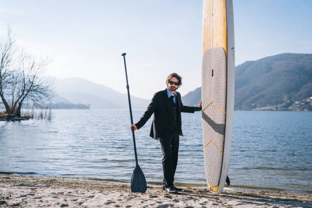 istock Business man with paddle board relaxes on sunny beach in the morning 1308296607