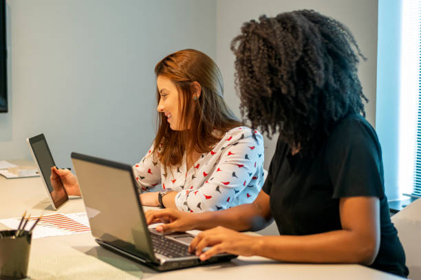 istock Two young women talking in an office. 1308297366