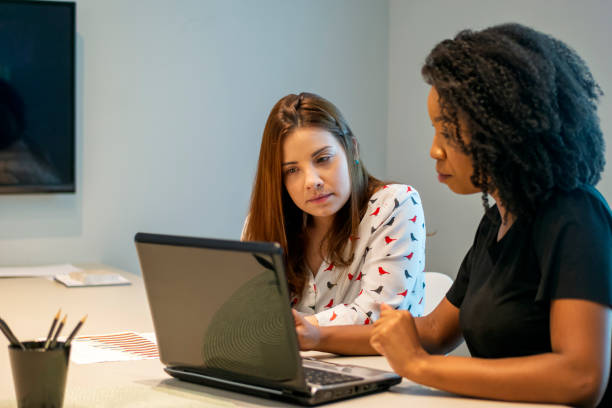 istock Two young women talking in an office. 1308297455