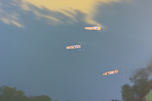 Aerial top view of a tourist paddling a wooden raft, kayak, or boat in river in national park in Thailand. People lifestyle adventure activity.