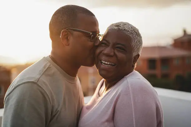 Photo of Happy african couple having tender moment outdoors at summer sunset - Focus on woman face