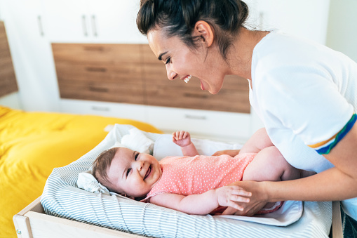 Young mother with her cute little baby girl, playing and make her smile