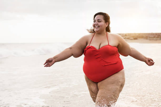 istock Plus size woman walking on the beach and having fun during summer vacation - Focus on face 1308301576
