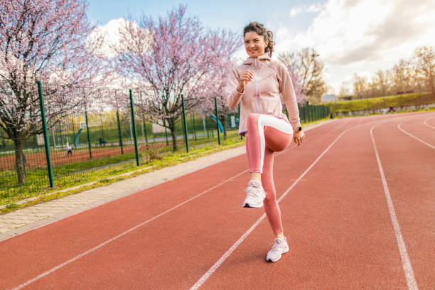 joven deportiva calentando en pista de atletismo. - running track women running spring fotografías e imágenes de stock