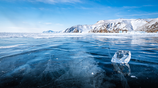 Glittering in the sun, the ice floe lies on the endless Baikal ice covered with cracks.