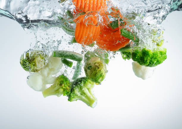 istock Vegetables falling into water with splashes and air bubbles. 1308303172