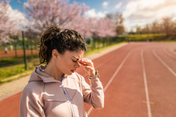 joven deportiva que tiene dolor de cabeza - running track women running spring fotografías e imágenes de stock