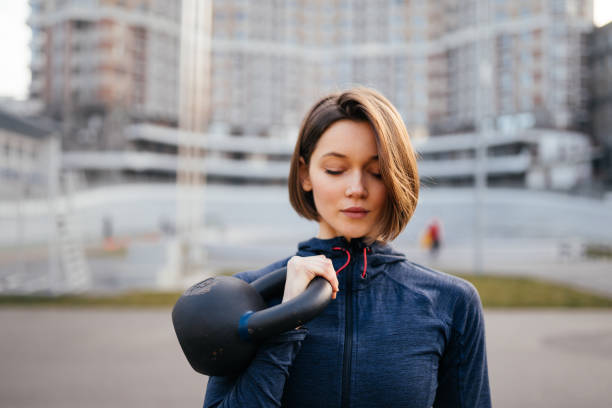 istock Young woman exercising with a kettlebell outside at stadium 1308304274