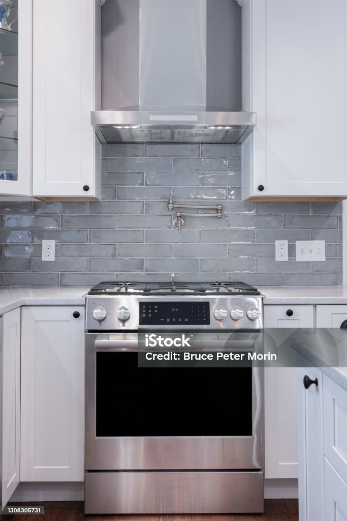 Kitchen gas stove and oven with exhaust vent hood Photograph of a kitchen gas stove and oven with vent hood Appliance Stock Photo