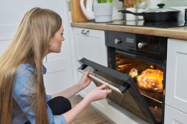 istock Young woman putting marinated chicken in baking bag in oven 1308309465