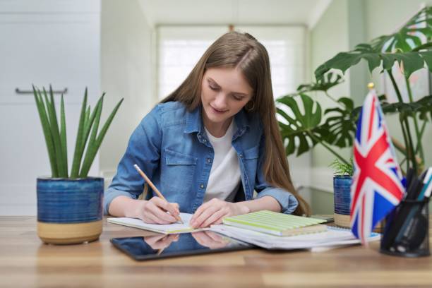istock UK learning English online. Female student remotely looking at webcam 1308309761
