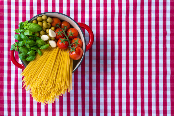 istock Spaghetti basil tomato garlic and olives in pot on gingham tablecloth 1308310948