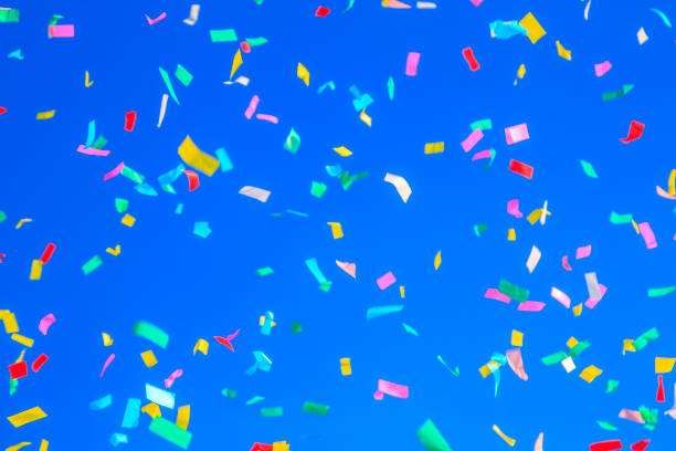 istock multicolored confetti on clear blue sky background. Concept of h 1308311446