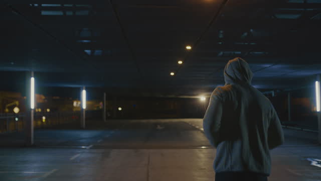 SLO MO Hooded jogger running on an empty car park