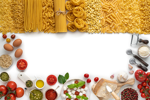 Assorted italian pasta raw uncooked with ingredients isolated on white copy space with spaghetti, tagliatelle, penne, fusilli, farfalle, tortellini, tortiglioni