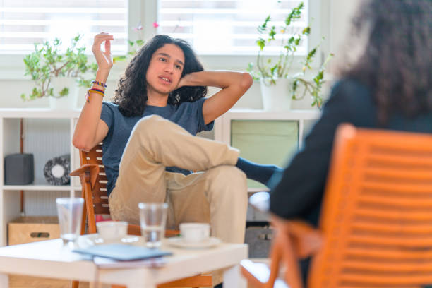 joven paciente hispano masculino escuchando psicoterapeuta femenina en su oficina - alternative therapy fotografías e imágenes de stock