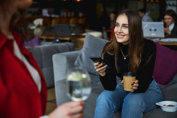 istock Charming young woman using cellphone and talking with colleague 1308315079