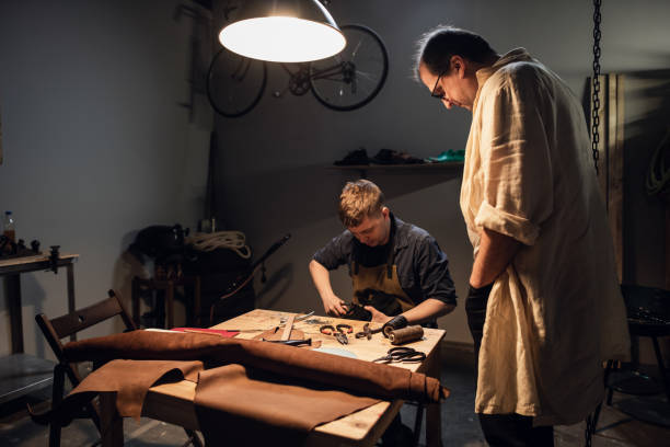 istock an experienced shoemaker and his assistant in their workshop make shoes from leather to order 1308317140