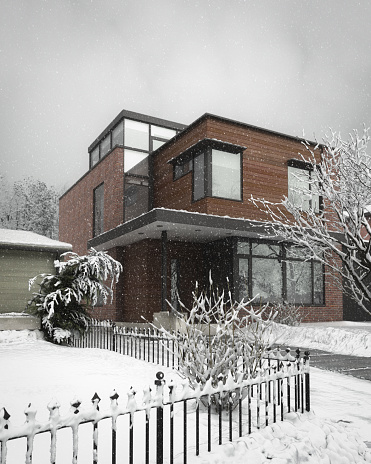 Suburban house with snow on the ground and more falling