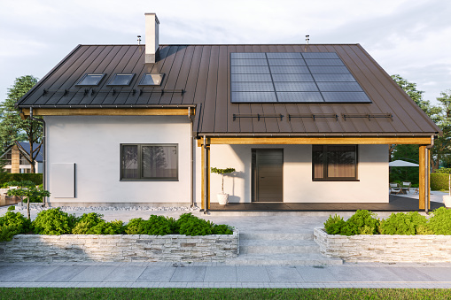 Modern house with solar panels and wall battery for energy storage.