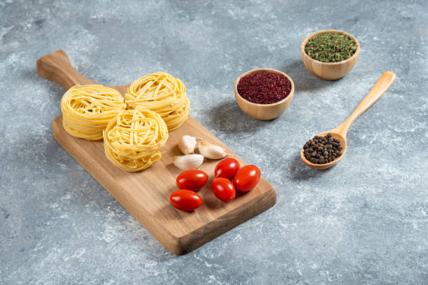 istock Pasta nests, garlic and cherry tomatoes on wooden board 1308324156