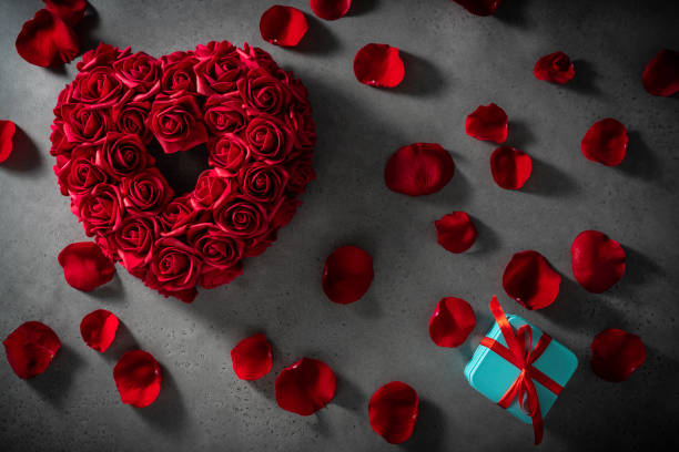 istock Valentines red rose flower petals heart shape on gray copy space and gift box 1308325041