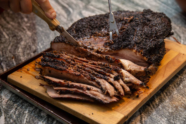 slicing a beef brisket fresh off of the smoker A juicy beef brisket, fresh off the smoker, being sliced on a board on the counter, for a weekend dinner at the cottage. part of series carving food photos stock pictures, royalty-free photos & images