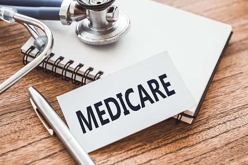 MEDICARE - text on card on wooden table with stethoscope and notepad for medical records.