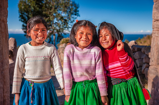 Three Peruvian little girls on Taquile Island, Lake Titicaca, Peru. Taquile is an island on the Peruvian side of Lake Titicaca 45 km offshore from the city of Puno. About 1,700 people live on the island, which is 5.5 by 1.6 km in size (maximum measurements), with an area of 5.72 km2. The highest point of the island is 4050 meters above sea level and the main village is at 3950 m. The inhabitants, known as Taquilenos, are southern Quechua speakers. Taquilenos run their society based on community collectivism  and on the Inca moral code ama sua, ama llulla, ama qhilla, (Quechua for 