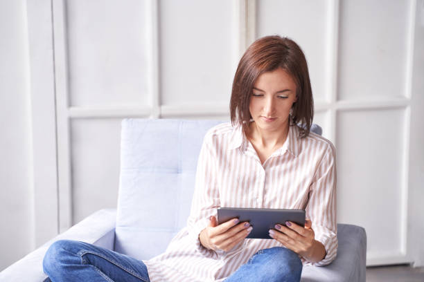 istock Young woman sitting at chair. Working on tablet. Online study concept 1308332948