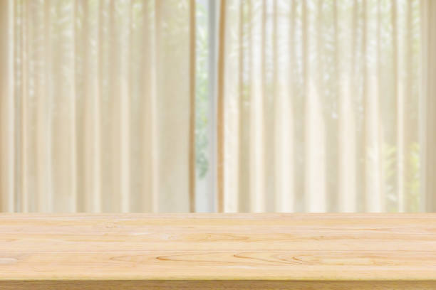 istock Empty wood table top with window curtain abstract blur background for product display 1308333435