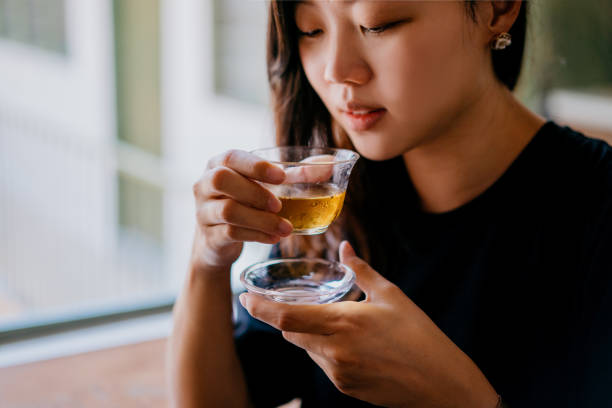 joven asiática tomando una taza de té chino en café - tea women beauty pampering fotografías e imágenes de stock