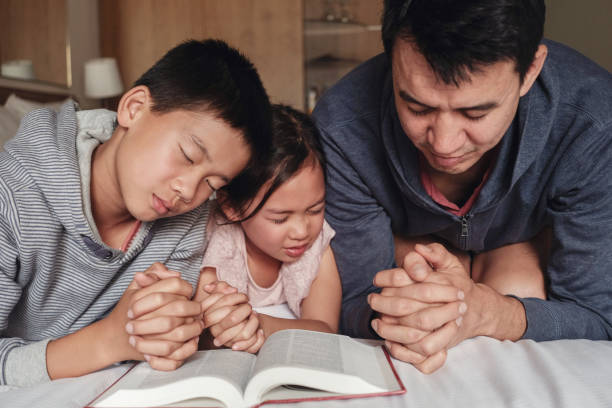 niños y padre padre padres orando con biblia en la cama, la familia ora juntos, iglesia en línea, iglesia de origen - rezar fotos fotografías e imágenes de stock