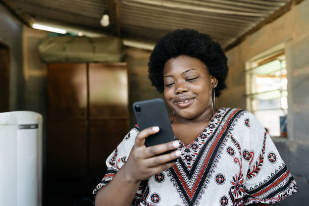 mujer africana usando teléfono inteligente en casa - frizzy 20s adult african descent fotografías e imágenes de stock