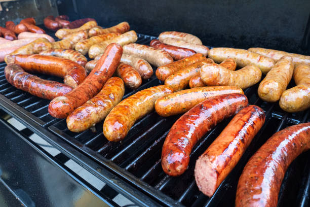 Grilling Sausage Fresh sausage and hot dogs grilling outdoors on a gas barbeque grill. saturated fat stock pictures, royalty-free photos & images