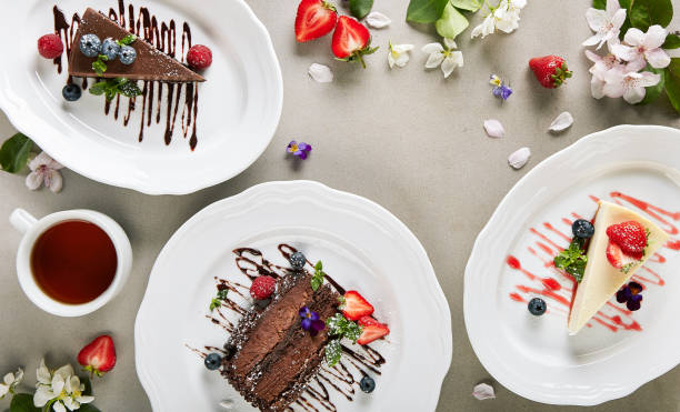 istock Dessert Table - created with Chocolate Cake, Classic Cheesecake and Chocolate Cheesecake. Fresh spring flowers on vintage table with berries and tea cup. Cake slice topped with berries and chocolate sauce. 1308355756