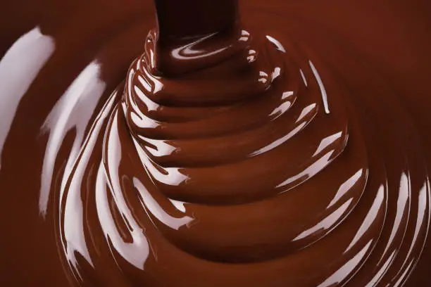 swirl hot chocolate. flowing sweet syrup, dark chocolate background