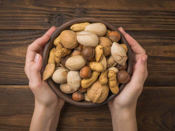 istock Women's hands hold a clay bowl with a mixture of nuts. 1308360783