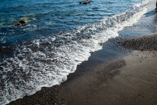 perissa black sand beach - black sand beach santorini greece stock-fotos und bilder
