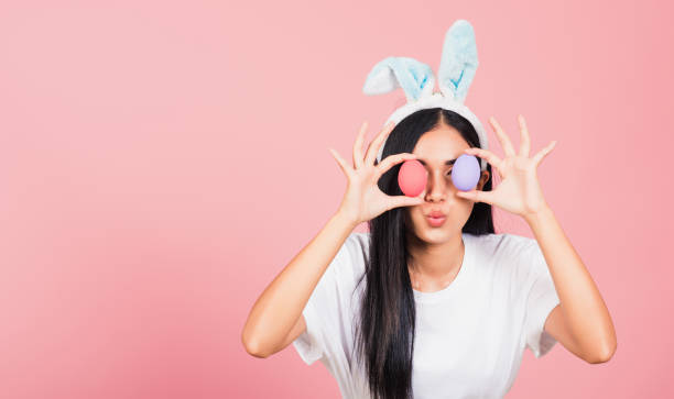 istock woman smiling wearing rabbit ears holding colorful Easter eggs front eyes 1308362424