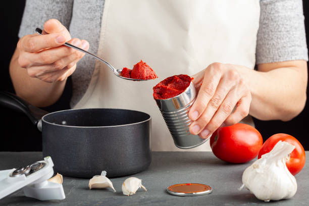 istock A caucasian woman is adding tomato paste from a can into a dish she is preparing 1308362766