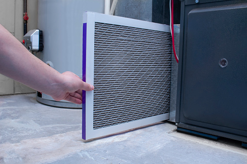 Una persona cambiando un filtro de aire en un horno de alta eficiencia photo