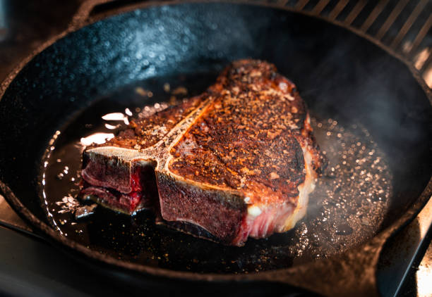 T-bone steak frying on cast iron pan