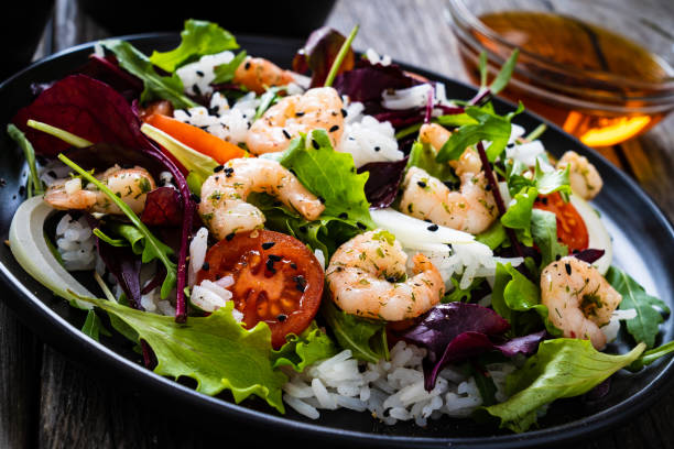 istock Prawn salad - prawns with white rice and vegetables on wooden table 1308365433