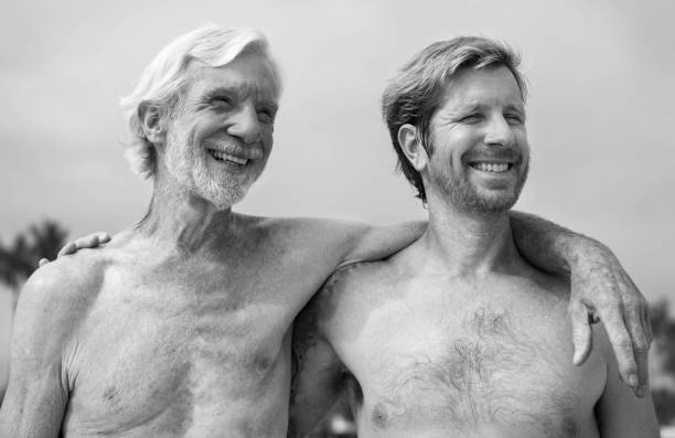 Grandad and dad with arms around each other smiling. Father and son love. Father and son happy togehter hanging out outdoor. Acitive and fit. gay daddy stock pictures, royalty-free photos & images
