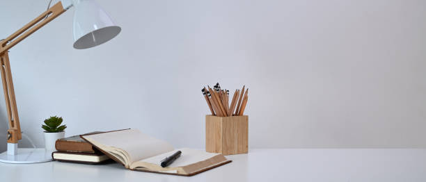 istock Simple workplace with lamp, pencils holder, notebook and cactus on white desk at home office. 1308366847