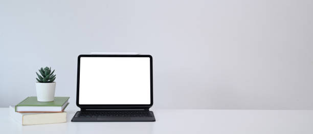 istock Minimal workplace with computer tablet, books, plant and copy space on white table. 1308366887