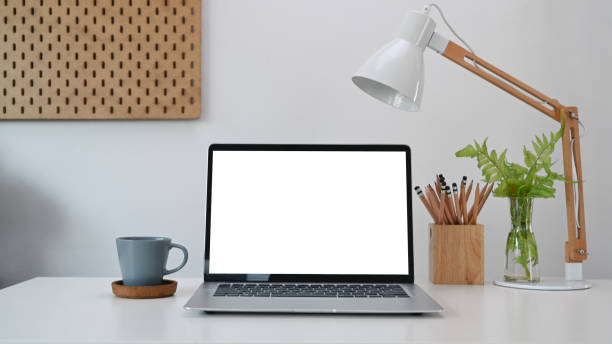 istock Simple workplace with computer laptop coffee cup, house plant and pencils holder on white table. 1308366912
